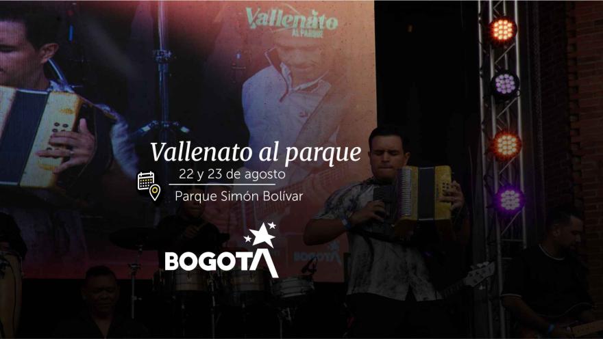 A musician on stage playing a yellow accordion in front of giant video screens.
