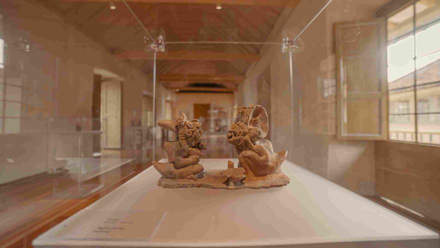 Pieza arqueológica de cerámica exhibida en una vitrina del Museo Arqueológico de Bogotá, con figuras antropomorfas finamente elaboradas, en una sala iluminada que resalta el valor histórico y artístico de las culturas prehispánicas de Colombia.
