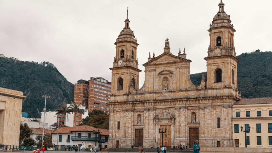  Vista frontal de la Catedral Primada de Colombia, ubicada en la Plaza de Bolívar de Bogotá. Su imponente fachada de estilo neoclásico, con dos torres campanario, se alza frente a la plaza, con los cerros orientales como telón de fondo.