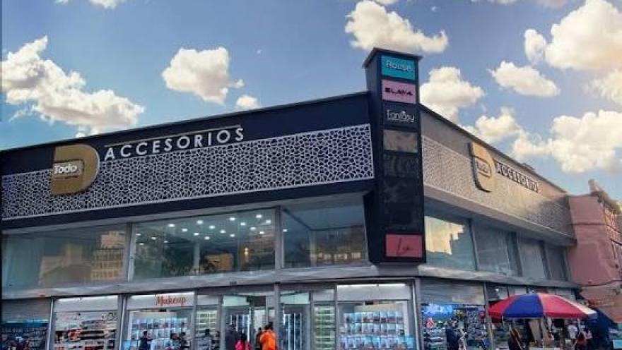 Fachada de un moderno centro comercial especializado en accesorios, con amplios ventanales, locales comerciales y una concurrida zona peatonal. Su diseño contemporáneo y la actividad del entorno reflejan el dinamismo comercial de San Victorino, en el centro de Bogotá.