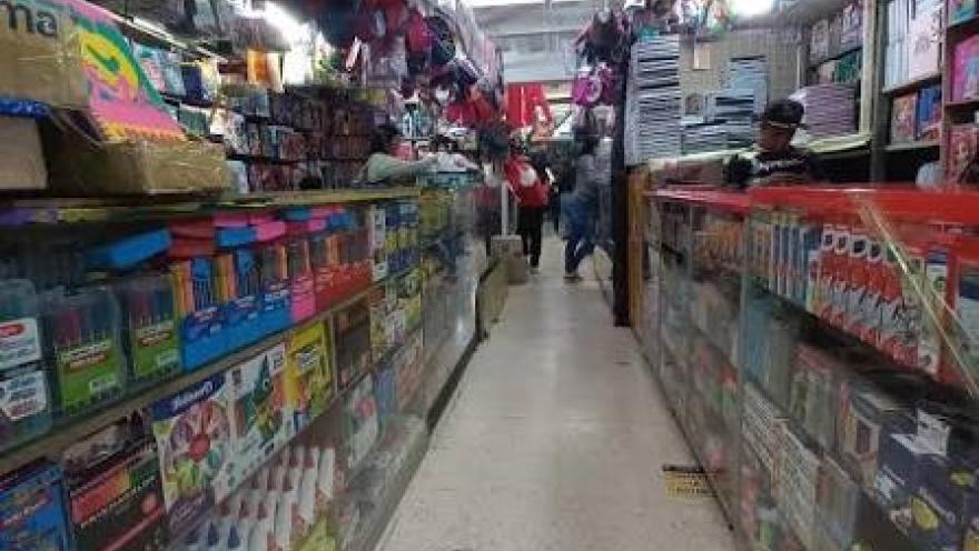  Pasillo interior de un centro comercial con locales especializados en papelería, útiles escolares y artículos de oficina. Las vitrinas repletas de productos y el constante tránsito de visitantes reflejan la amplia oferta comercial característica de San Victorino, en el centro de Bogotá.