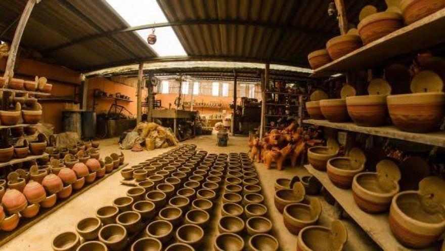Taller artesanal en Ráquira con estanterías llenas de piezas de cerámica y vasijas de barro elaboradas a mano por artesanos locales.