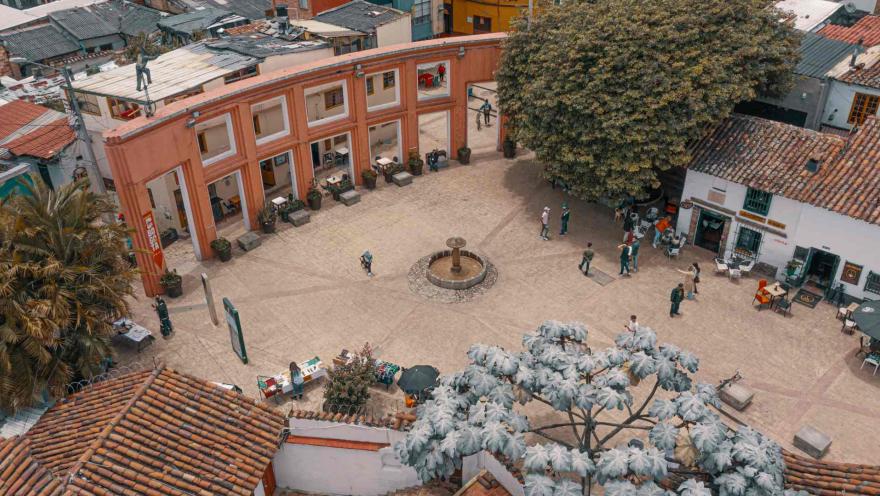 Vista aérea de la Plaza del Chorro de Quevedo, en el barrio La Candelaria de Bogotá. El espacio, rodeado de arquitectura colonial, árboles y cafés, reúne a visitantes que disfrutan del ambiente histórico y cultural de uno de los lugares más emblemáticos de la ciudad.