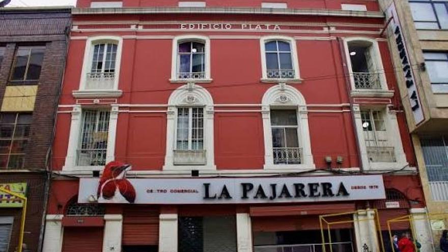 Fachada del Centro Comercial La Pajarera, un edificio de estilo tradicional con llamativos tonos rojos y detalles arquitectónicos clásicos. Ubicado en San Victorino, es uno de los referentes comerciales del centro de Bogotá y un destino reconocido para realizar compras de moda y diversos productos.