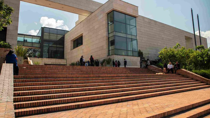 Vista frontal del Archivo de Bogotá, con amplias escalinatas de ladrillo, jardines y una moderna fachada de piedra y vidrio.