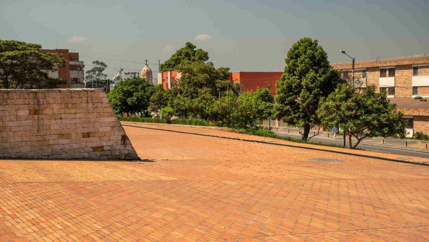 Plazoleta de ladrillo del Archivo de Bogotá, rodeada de árboles y con edificaciones del sector al fondo.