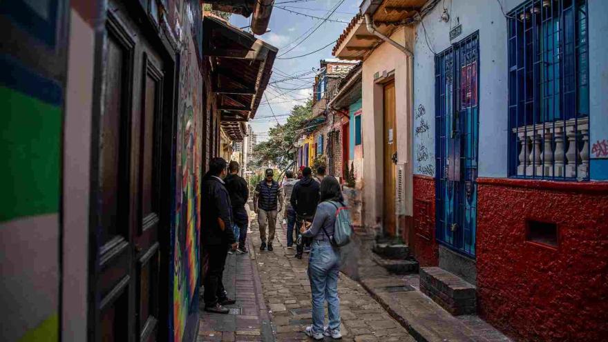 Callejón del Embudo en La Candelaria, con visitantes recorriendo su estrecha vía empedrada entre casas tradicionales de colores y arte urbano.