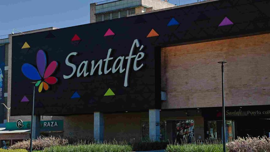 El colorido logo de Centro Comercial Santafé destaca sobre su moderna fachada, rodeada de amplias zonas verdes y espacios abiertos. Una imagen que refleja el carácter contemporáneo y acogedor de este importante punto de encuentro del norte de Bogotá.