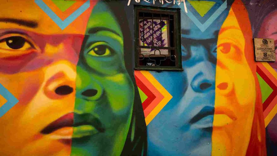 Mural de arte urbano en el Callejón del Embudo, con coloridos rostros y figuras que llenan de identidad y creatividad las paredes de La Candelaria.