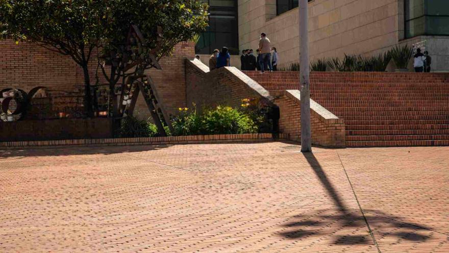 Escalinatas de ladrillo y jardines en el exterior del Archivo de Bogotá, con visitantes en la entrada del edificio.