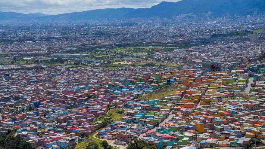 Vista panorámica de Ciudad Bolívar, con sus coloridas viviendas extendiéndose por las laderas y las montañas de Bogotá al fondo.