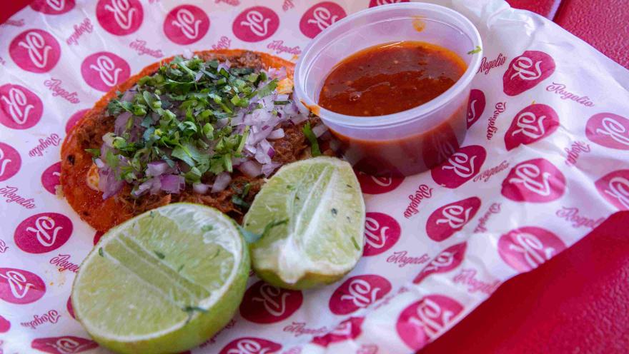 Tacos de birria con cebolla, cilantro, limón y salsa roja.