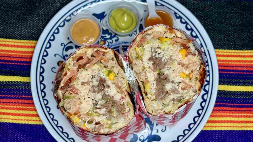 Burritos de Antojos Mexicanos servidos en papel decorativo, acompañados de tres salsas.