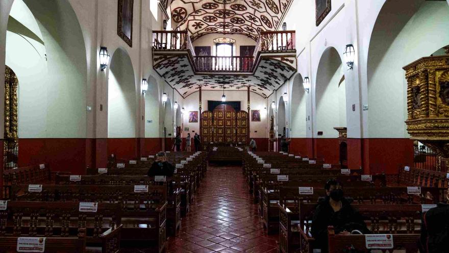 Interior de la Iglesia de San Juan de Dios, con naves laterales, bancas de madera, retablos dorados y un elaborado techo colonial decorado.