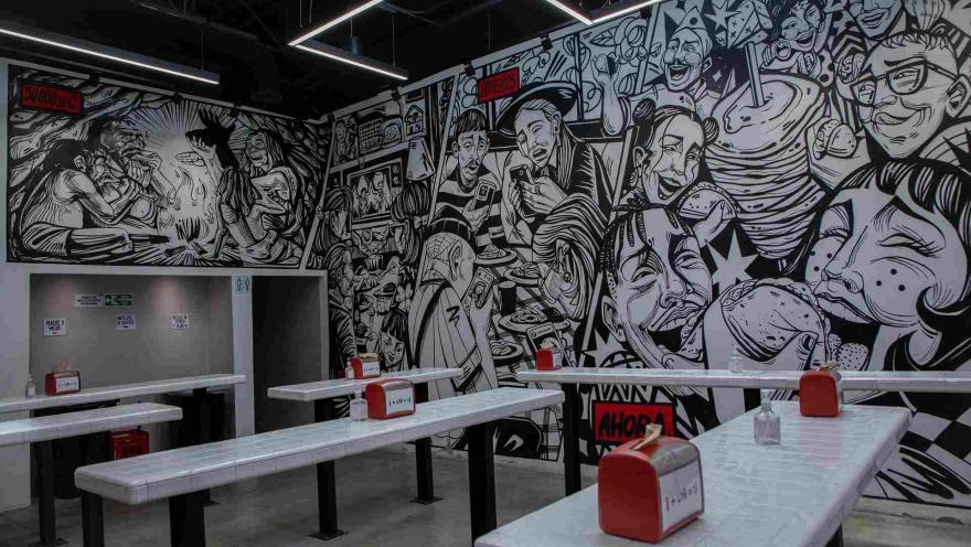Interior de Los Tacos Norteños con mural de temática mexicana y mesas para comensales.