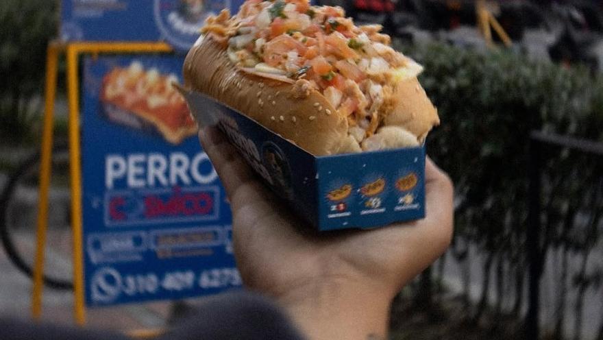 Perro caliente cargado de toppings y servido para llevar.
