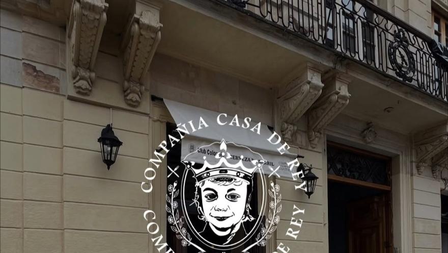 Fachada de estilo clásico con detalles ornamentales, balcón de hierro forjado y entrada de madera, identificada con el emblema de la compañía.