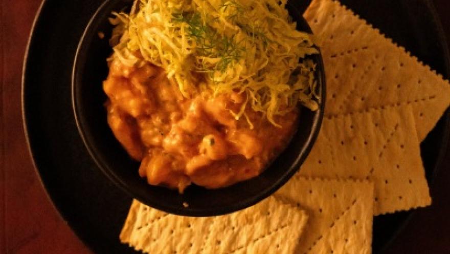 A creamy and hearty dish, served with crispy crackers and garnished with fresh herbs.