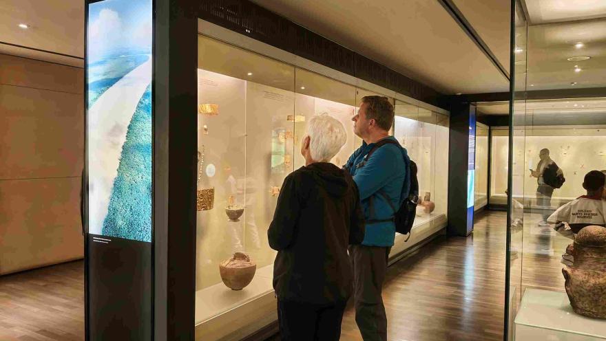 Visitantes recorren las salas del Museo del Oro y observan piezas arqueológicas exhibidas en vitrinas iluminadas.