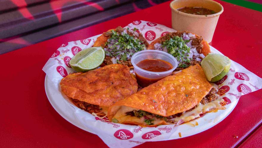 Variedad de tacos y quesadillas de birria acompañados de salsas y limón.