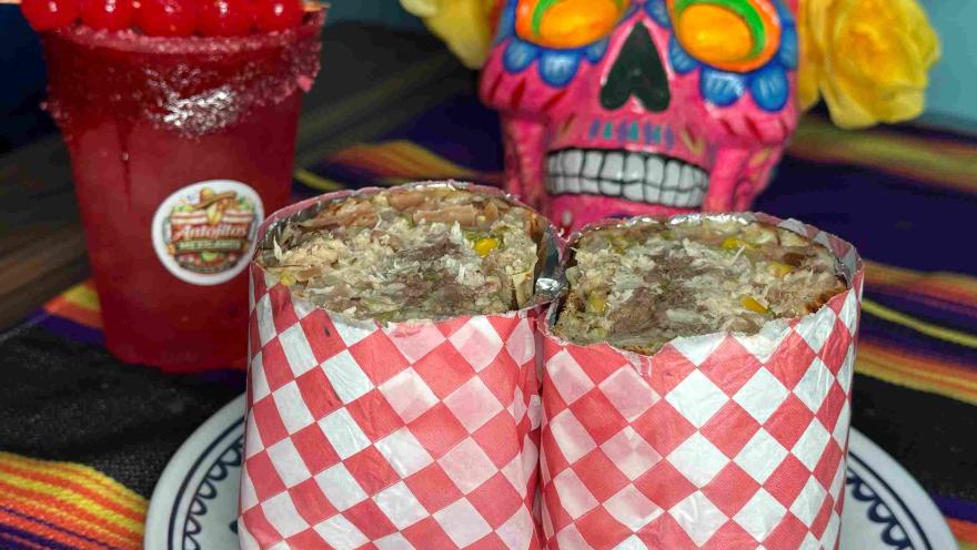  Burritos rellenos acompañados de una bebida roja y decoración alusiva a la cultura mexicana.