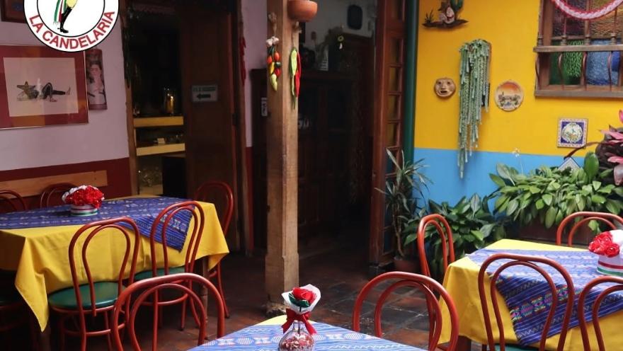 Interior patio of Enchiladas La Candelaria, decorated with bright colors, tables with Mexican tablecloths, plants, and traditional motifs.