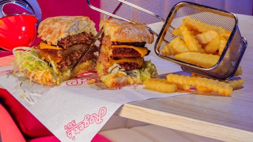Hamburguesa artesanal doble con queso, lechuga y salsas, acompañada de papas crocantes en estilo clásico.