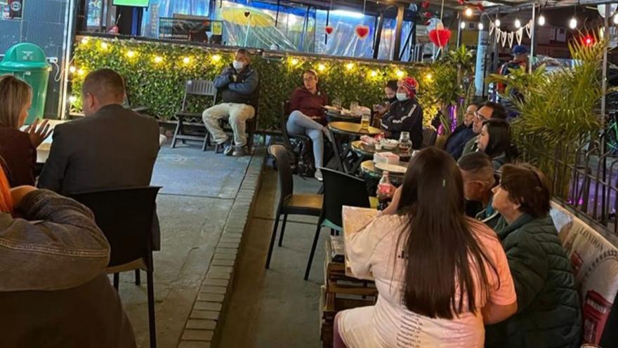 Espacio al aire libre de La Berraquera, con comensales compartiendo en un ambiente acogedor, rodeado de vegetación e iluminación cálida.