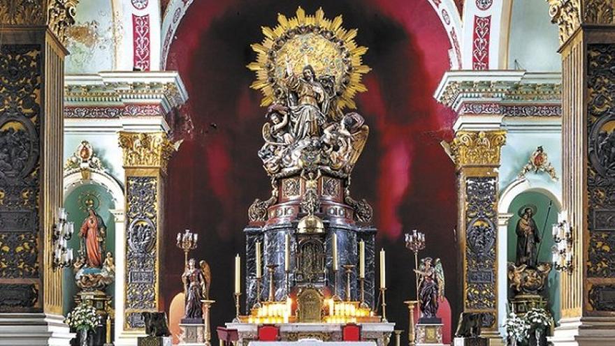 El altar mayor de la Iglesia del Voto Nacional destaca por su rica ornamentación dorada, esculturas religiosas y el imponente Sagrado Corazón de Jesús, rodeado de detalles decorativos que realzan la solemnidad del templo.