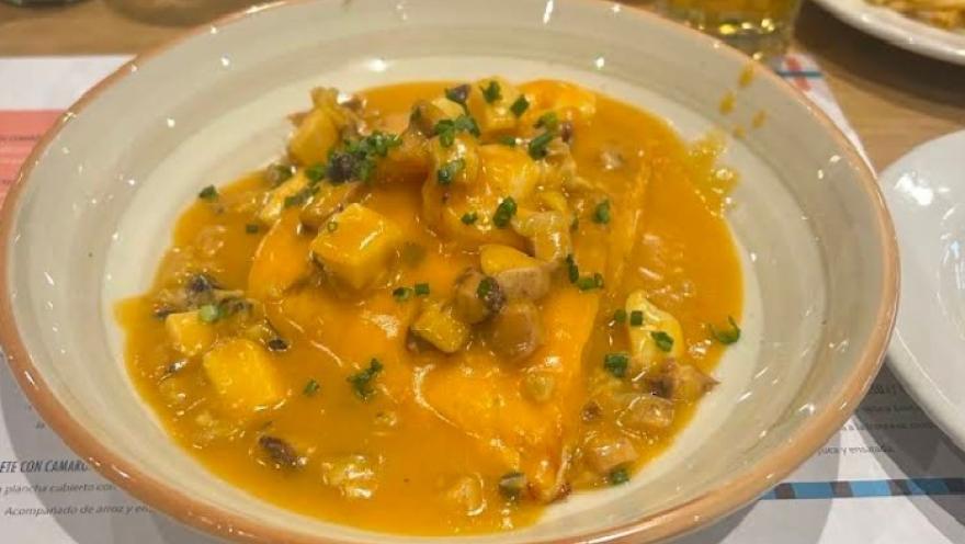 Plato de mariscos en salsa cremosa, acompañado de papas y decorado con hierbas frescas.
