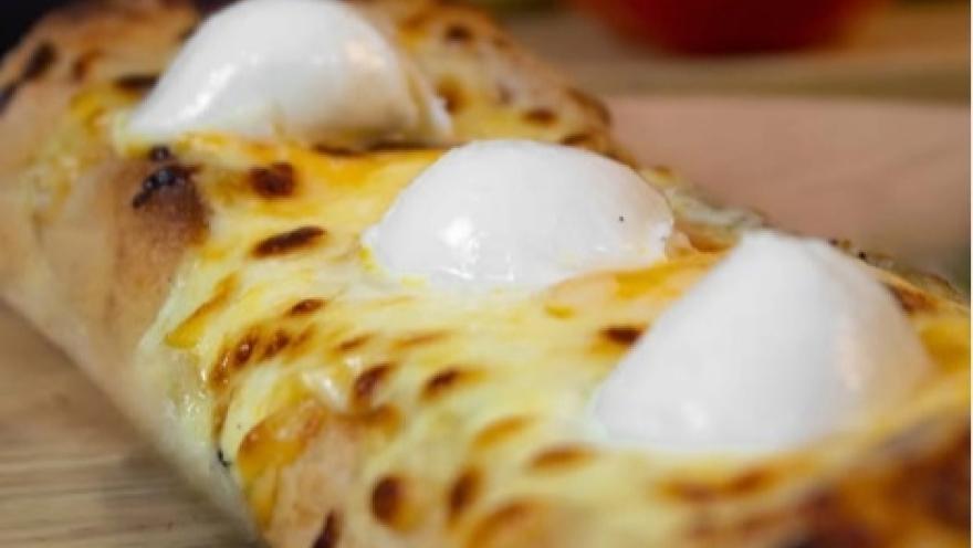 Pizza de masa madre cubierta con queso fundido y bocados de mozzarella.