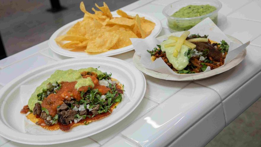 Tacos con carne, salsas, guacamole, cilantro y cebolla, acompañados de totopos.