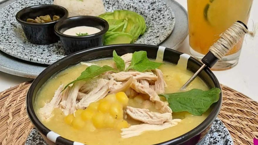 Ajiaco santafereño servido con pollo y papa, acompañado de arroz, aguacate, crema y otros complementos tradicionales.