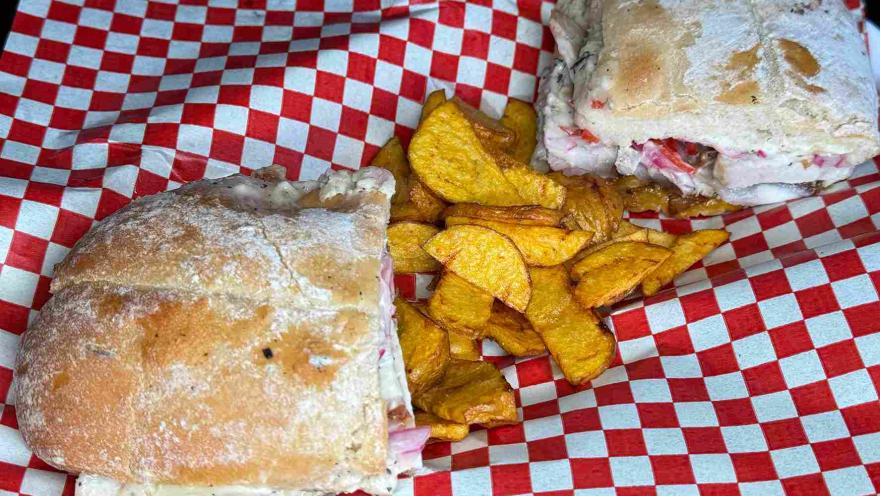 Sánduches de chicharrón servidos con papas crocantes sobre papel de cuadros rojos y blancos.