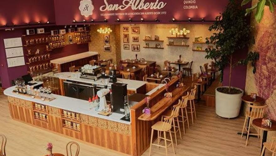 The spacious Café San Alberto interior, featuring a central bar, wooden furniture, and warm decor that highlights its coffee-making tradition.