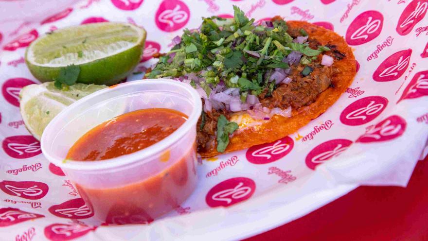 Taco de birria con queso, cebolla, cilantro y salsa picante.
