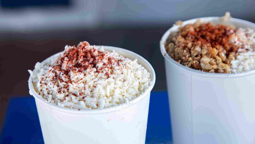 Vasos de esquites preparados con queso y chile en polvo.