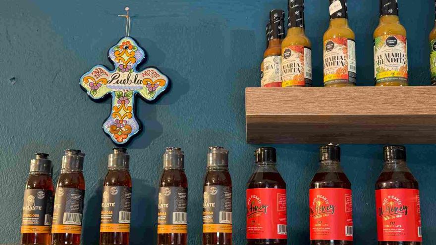 Variedad de salsas picantes y productos mexicanos exhibidos en estanterías decoradas.