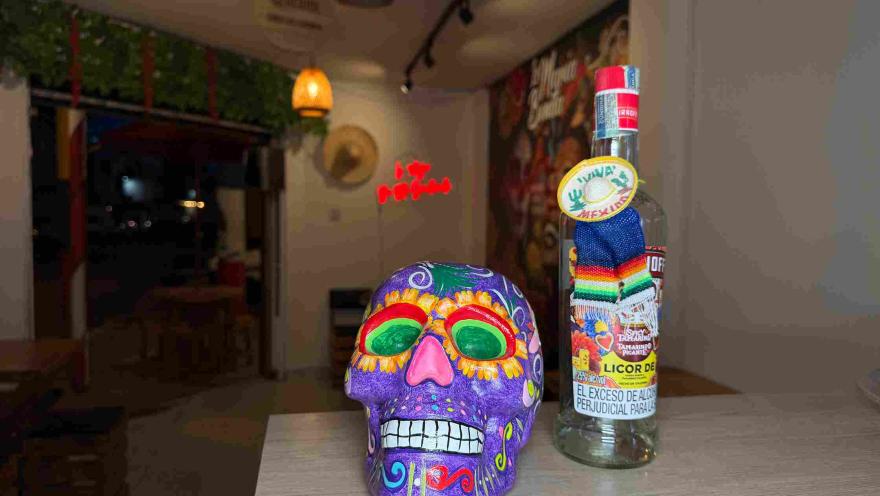 Decorative skull next to a bottle of liquor in a Mexican-inspired setting.