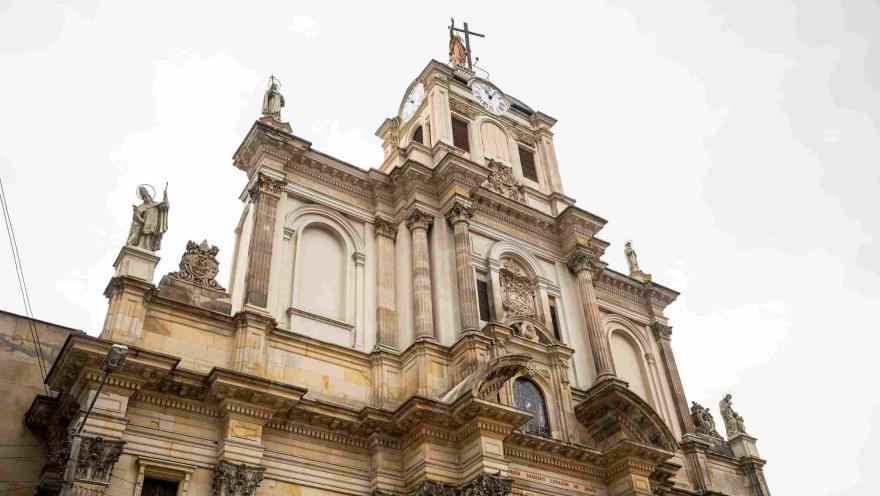  La imponente fachada de la Basílica Menor del Voto Nacional destaca por su arquitectura de inspiración neoclásica, sus columnas ornamentadas, esculturas religiosas y una torre central coronada por una cruz.