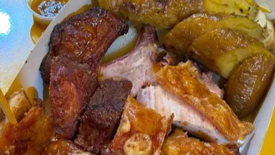 Plato con variedad de carnes asadas, acompañadas de plátano maduro y salsas, servido en una bandeja.