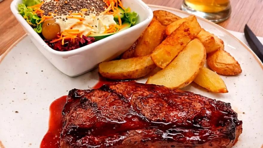 Glazed pork ribs accompanied by golden potatoes and salad.