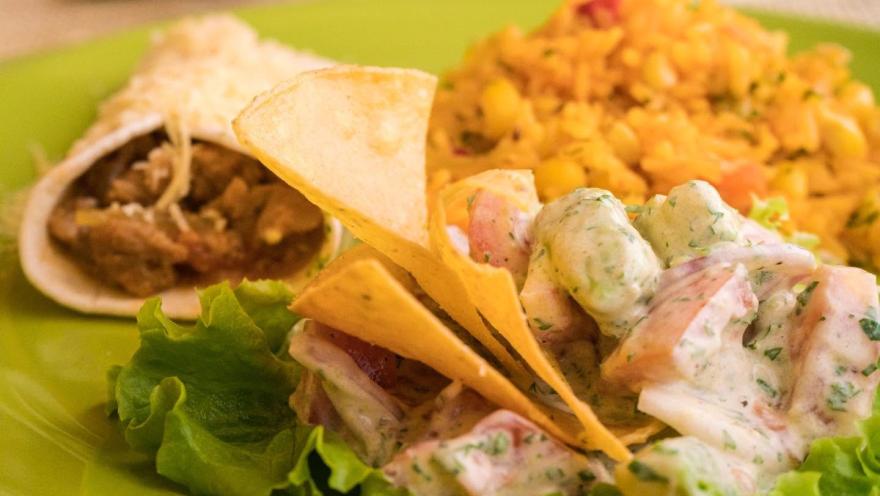 Plato vegetariano con ensalada de papa, arroz con vegetales, chips de tortilla y preparaciones a base de vegetales frescos.