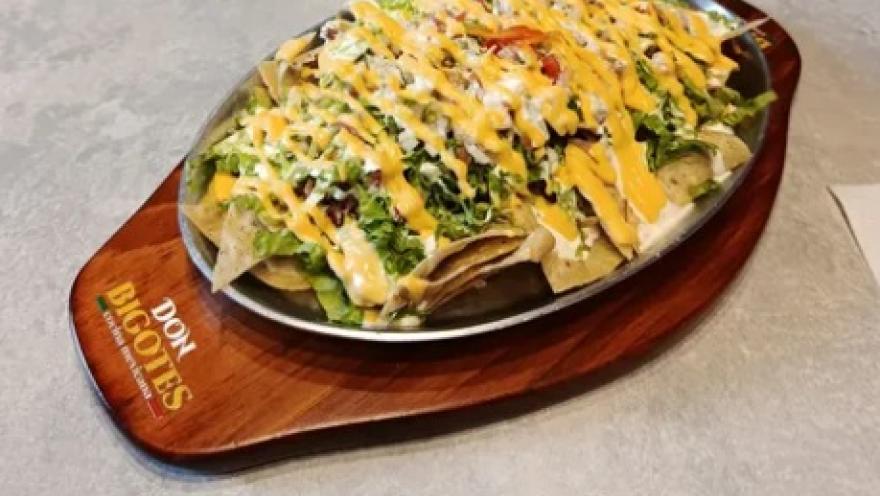 Nachos served with lettuce, beans, and cheese, topped with a creamy sauce.