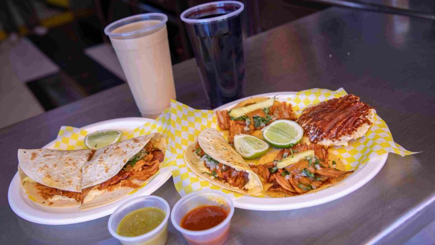 Variedad de tacos y quesadillas al pastor acompañados de salsas y bebidas.