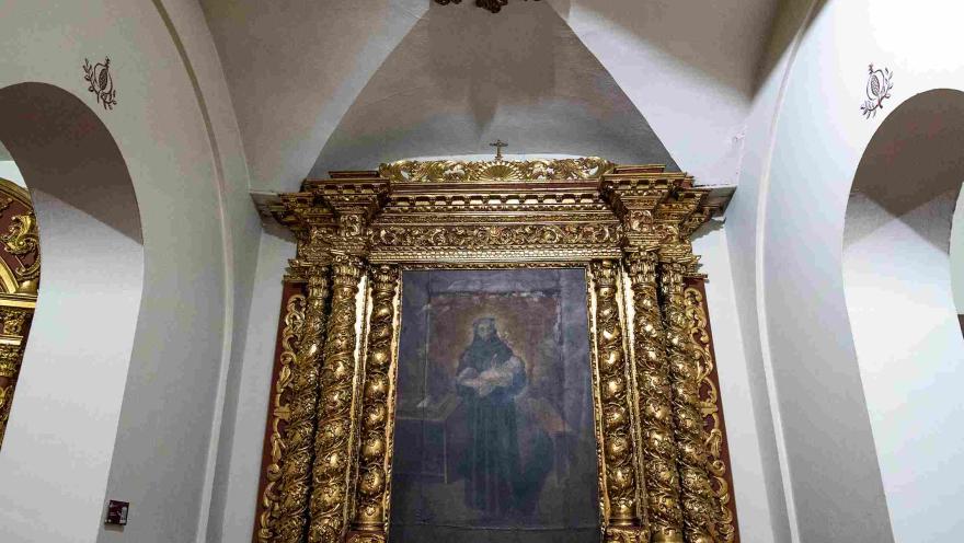 Retablo de estilo barroco con abundantes detalles dorados que enmarca una pintura religiosa en el interior de la iglesia de San Juan de Dios.