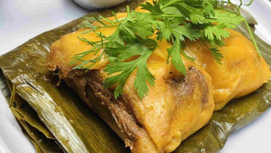 A traditional dish served on a banana leaf, with a golden and soft topping, accompanied by fresh herbs.
