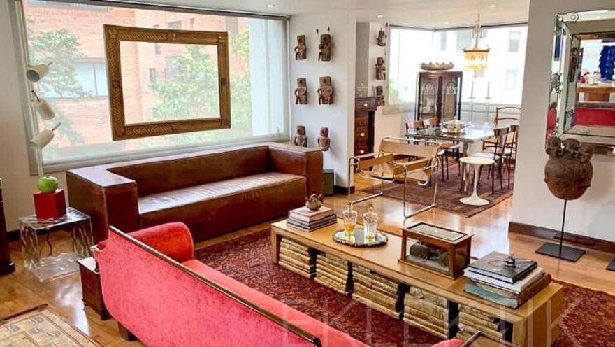 Elegante sala de estar con muebles de diseño, piezas de arte y antigüedades que crean un ambiente sofisticado y acogedor.