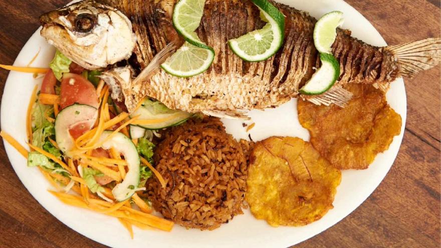 Pescado frito entero acompañado de arroz, patacones, ensalada fresca y rodajas de limón.