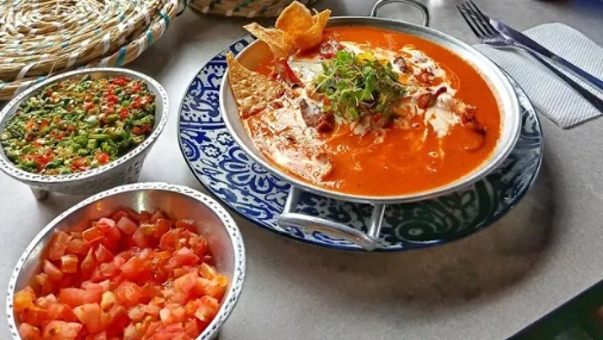 Enchiladas smothered in red sauce, accompanied by guacamole and pico de gallo.